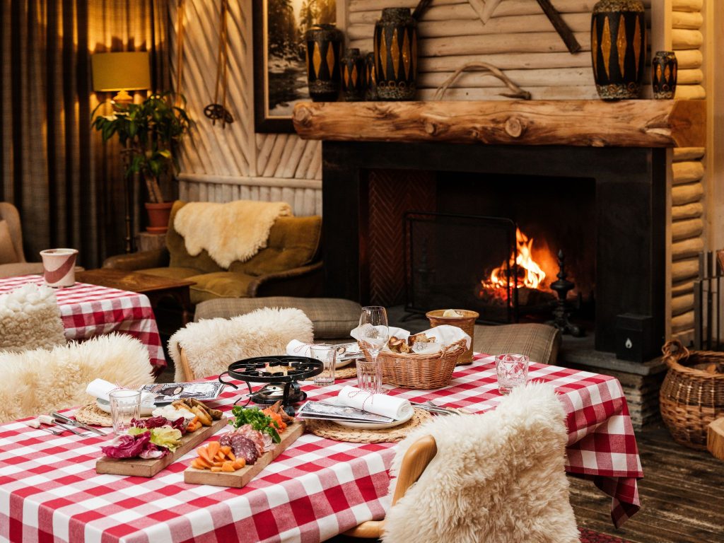 A table with a red gingham tablecloth in a wood panelled room with a fireplace