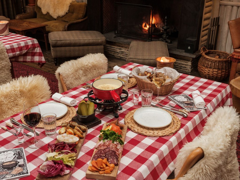 Fondue on a table with a gingham tablecloth and a fireplace in the background