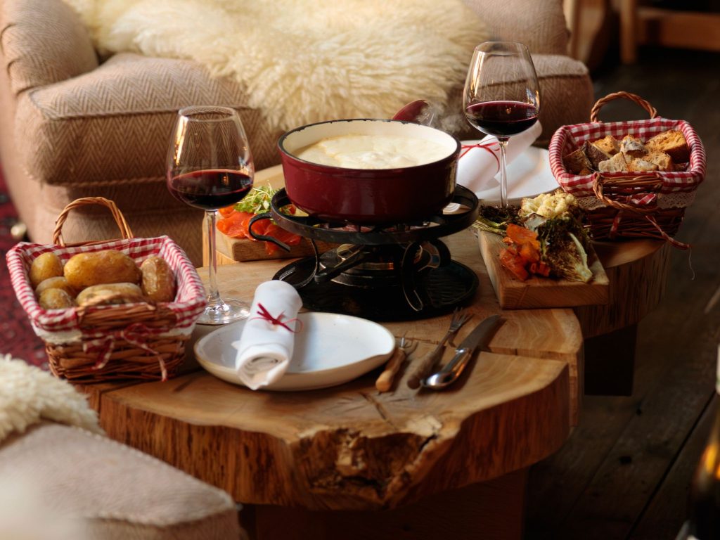Fondue with bread and glassed of wine set on a table