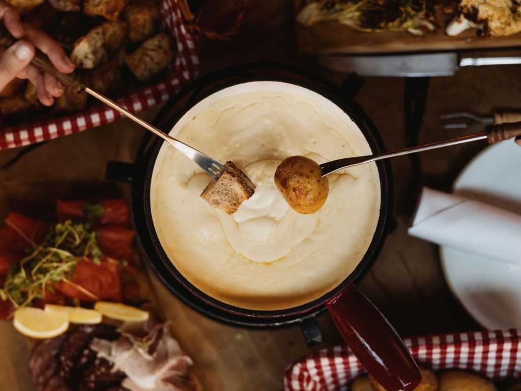 Bread and potatoes being dipped in a fondue pot
