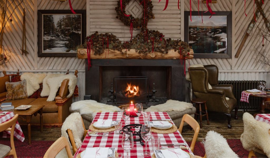 A table with a red gingham tablecloth in a wood panelled room with a fireplace
