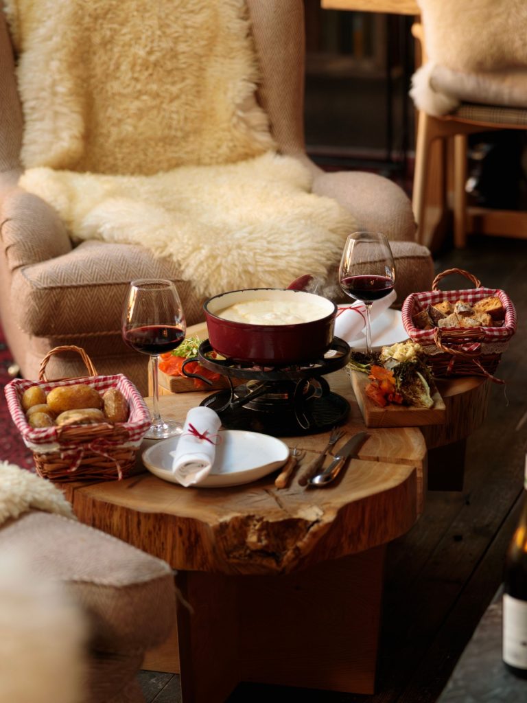 Fondue with bread and glassed of wine set on a table