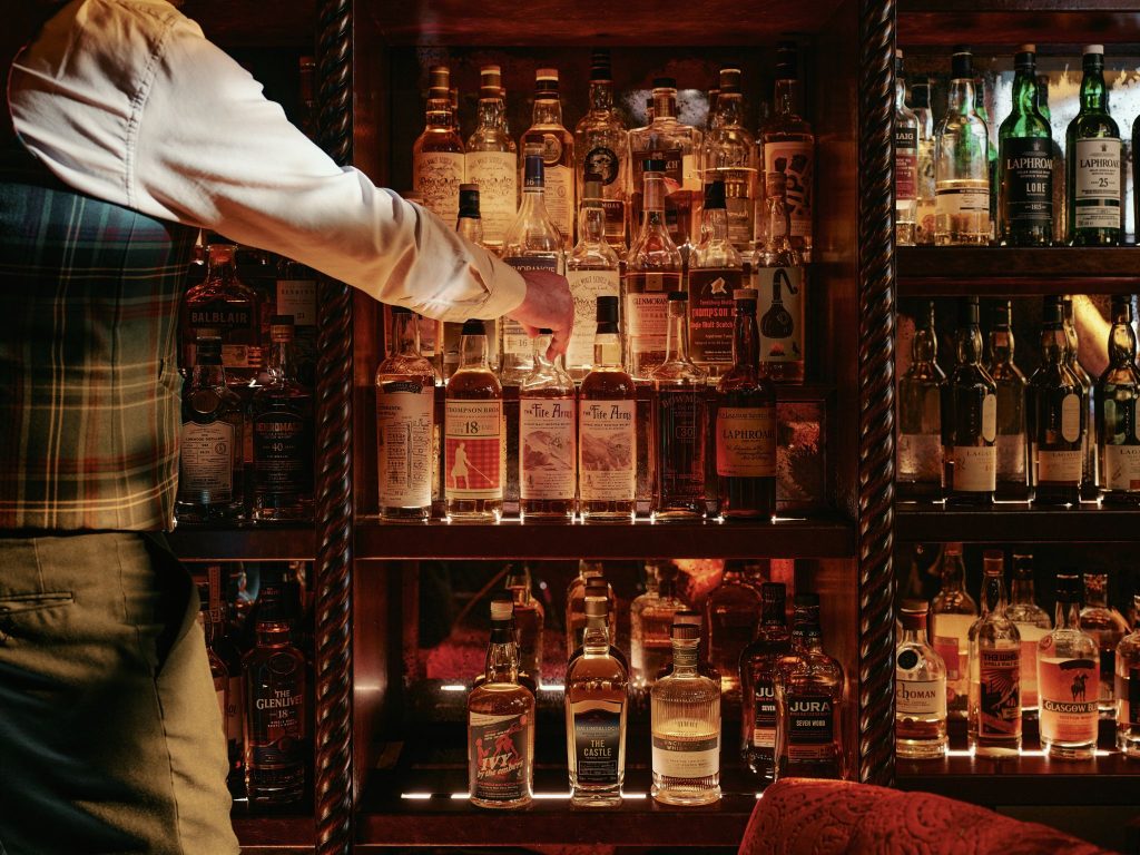 A man selecting a whisky bottle from well stocked shelves