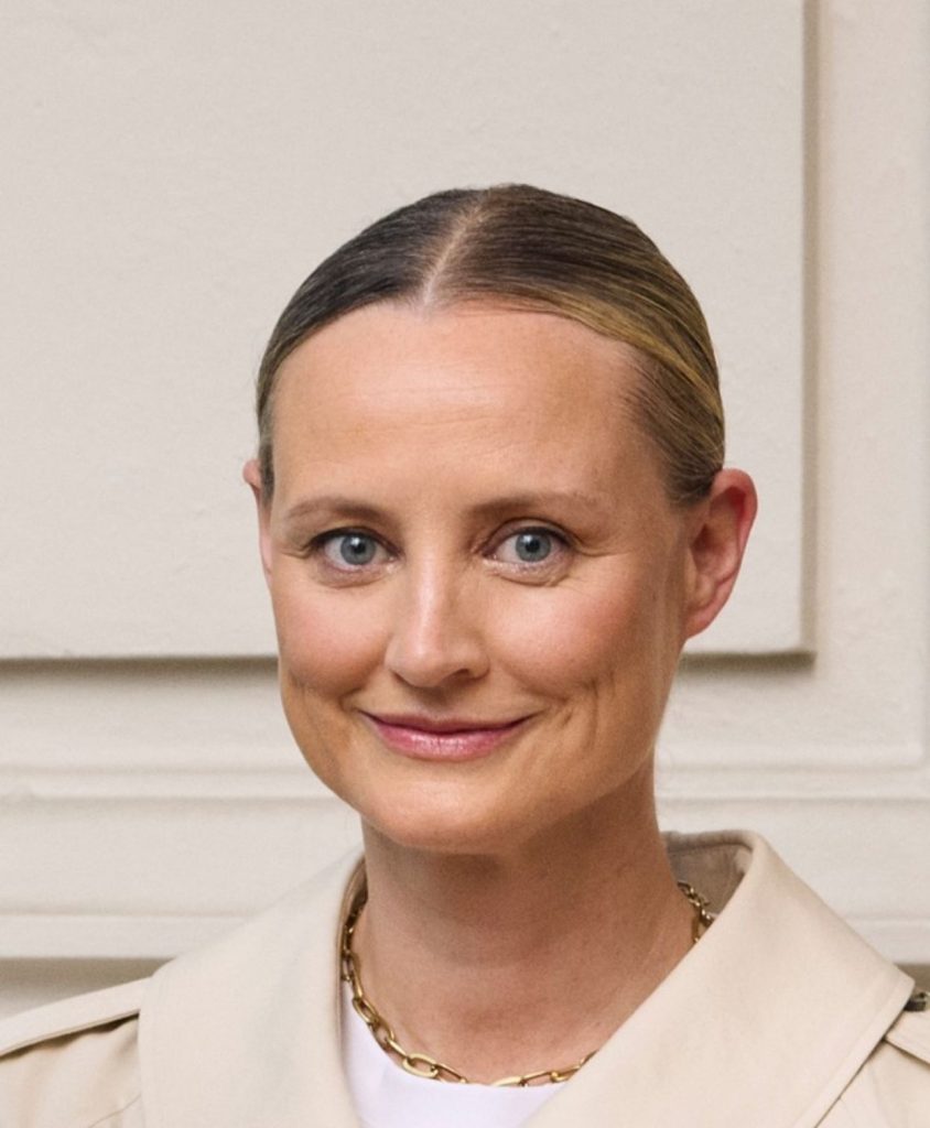 A smiling woman with dark blonde hair tied back