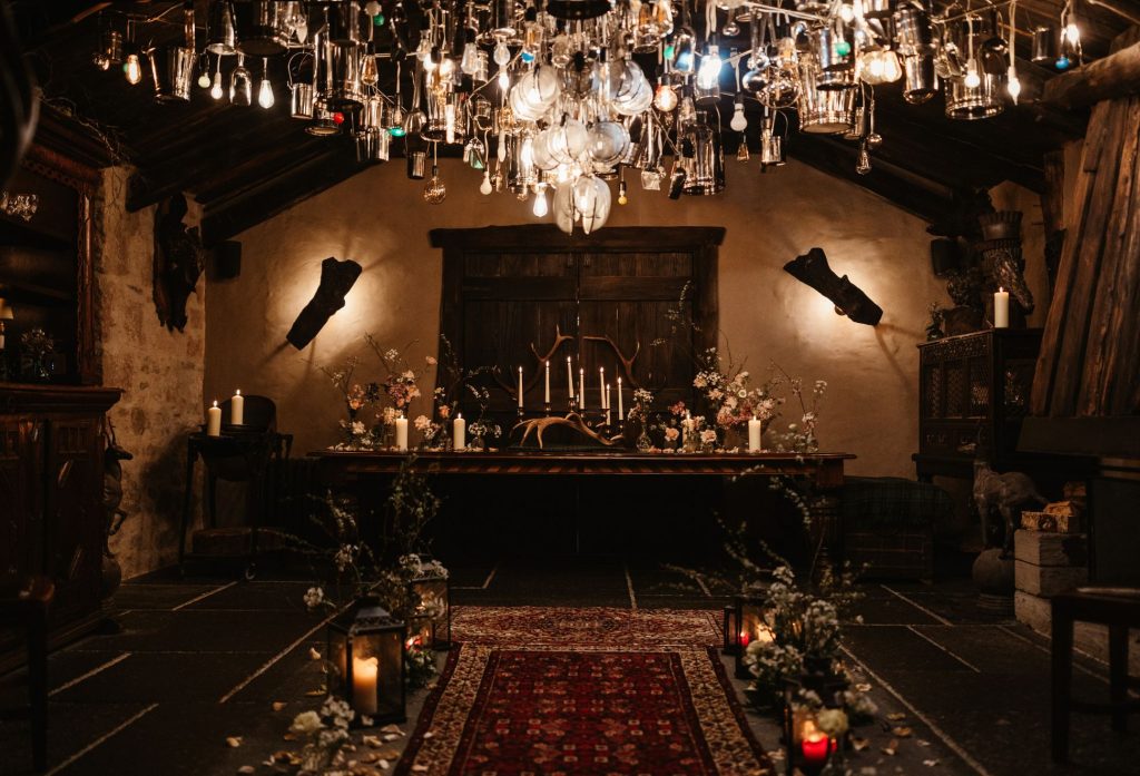 An atmospheric room set for an elopement, with a chandelier light installation overhead and candles lit