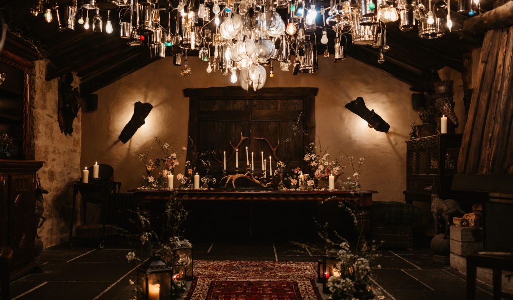 An atmospheric room set for an elopement, with a chandelier light installation overhead and candles lit