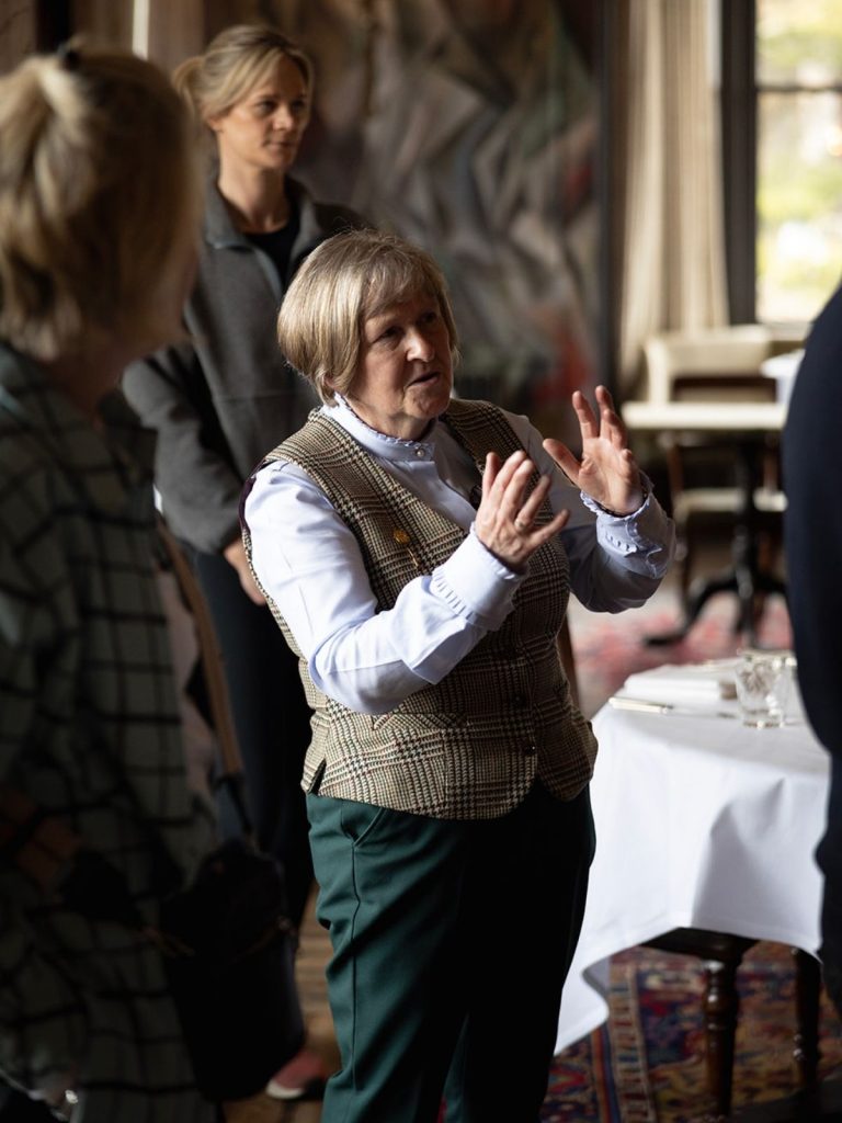 A woman in a tweed waistcoat leading a guided tour